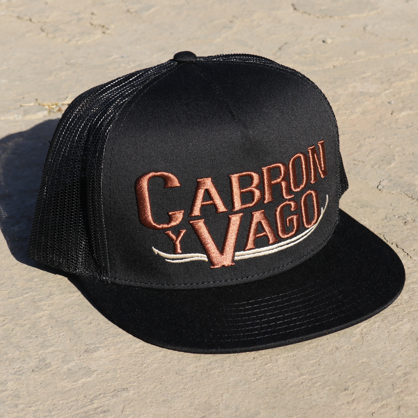 Cabron Y Vago black flat visor hat with brown embroidered logo and black mesh back.