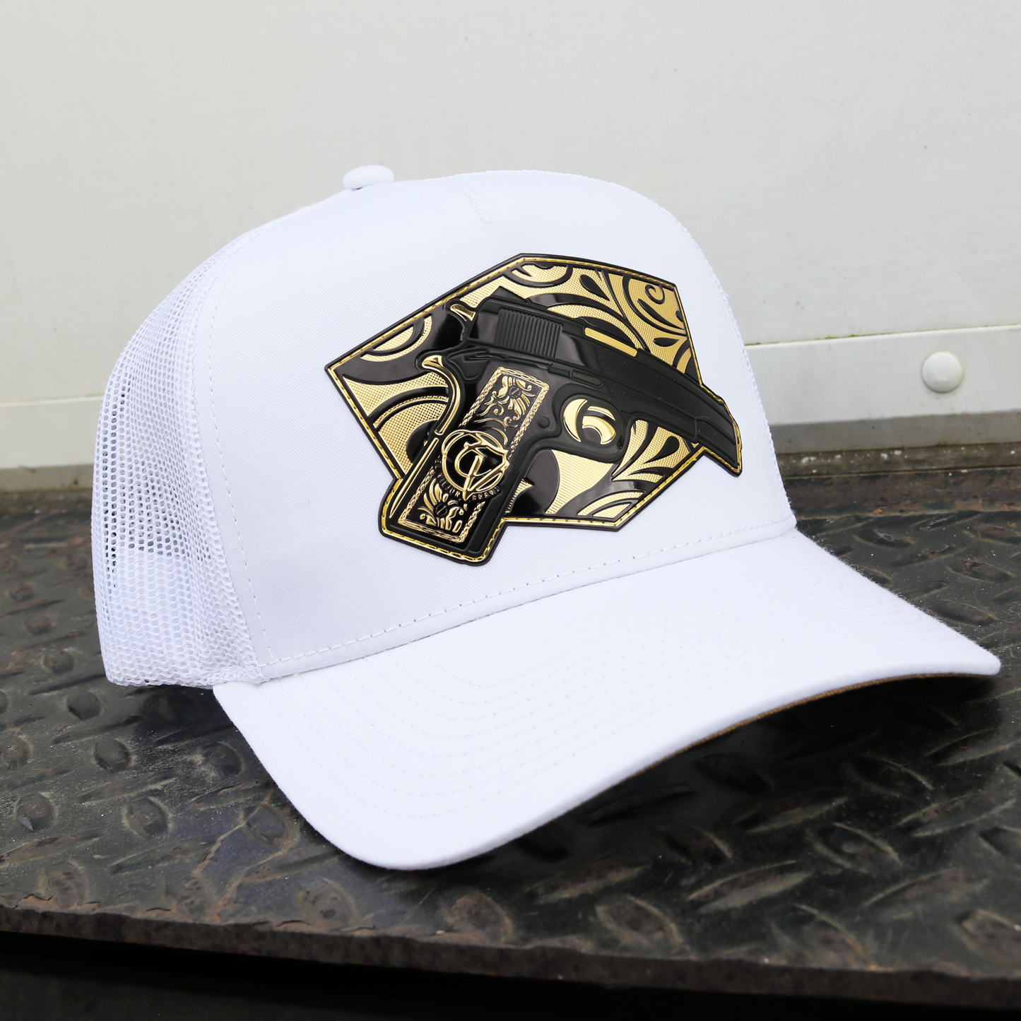 Gorra Cachas de Oro blanca con malla, perfil alto y parche de pistola negra y dorada.