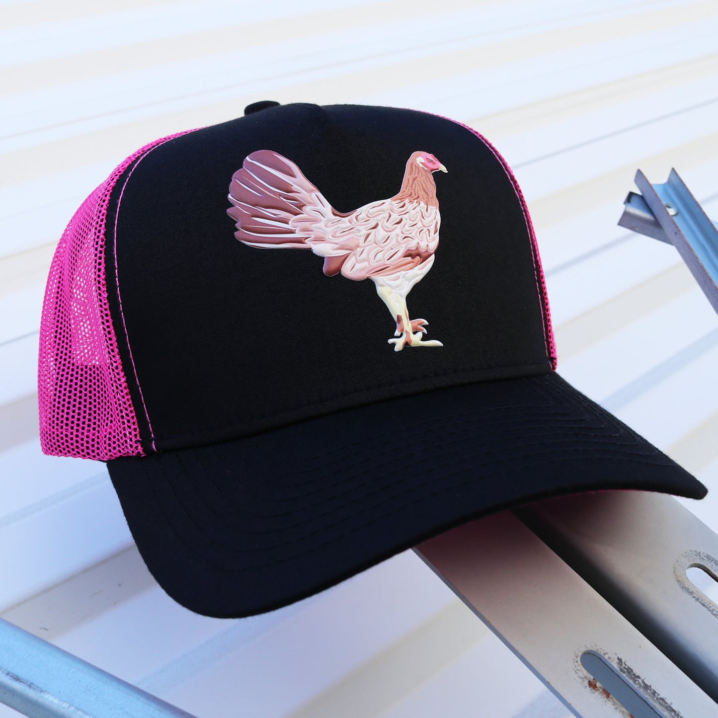 Mamá De Los Pollitos black and pink mesh trucker hat with a detailed hen graphic.