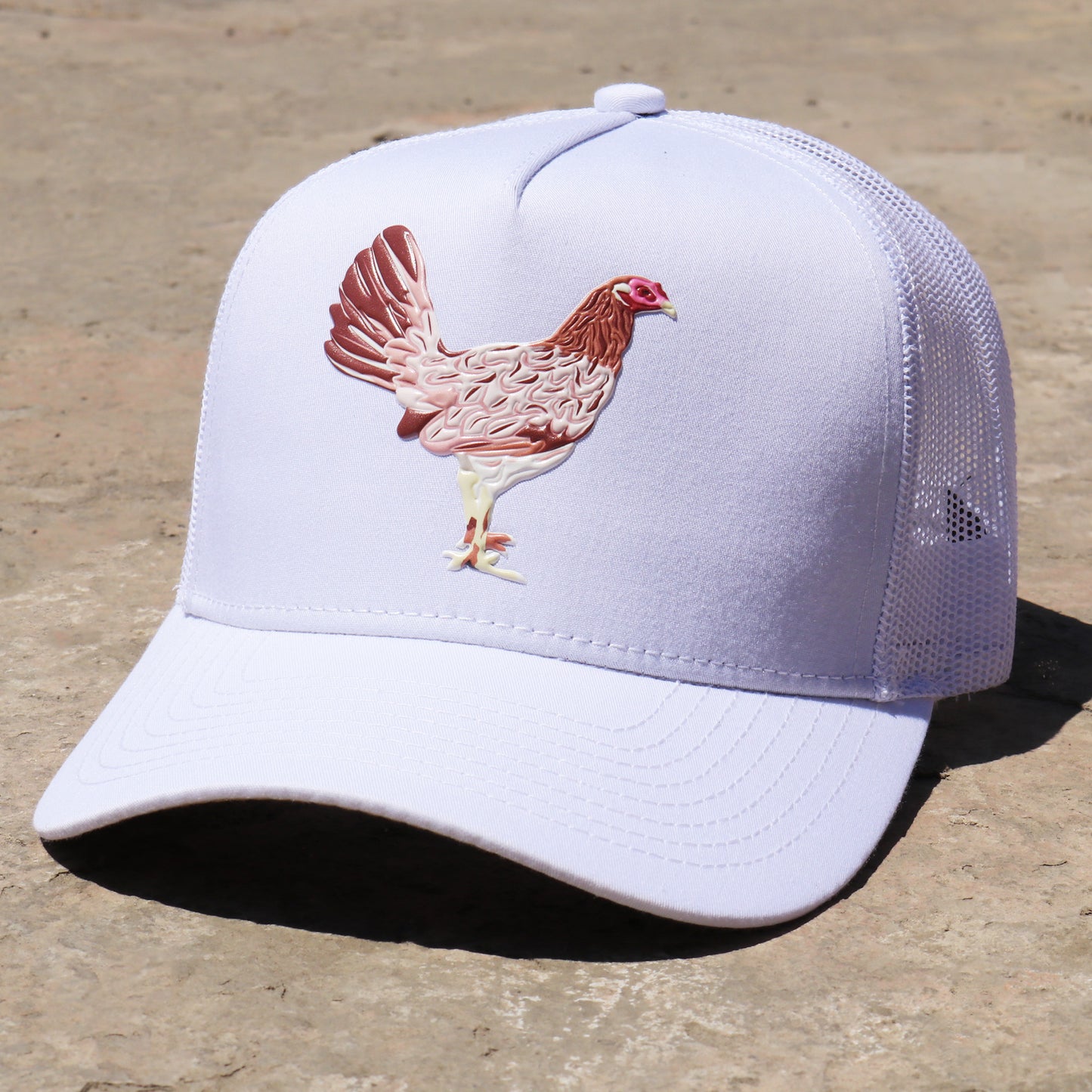White AVC trucker hat with a brown and pink hen design, pre-curved visor, and mesh back.