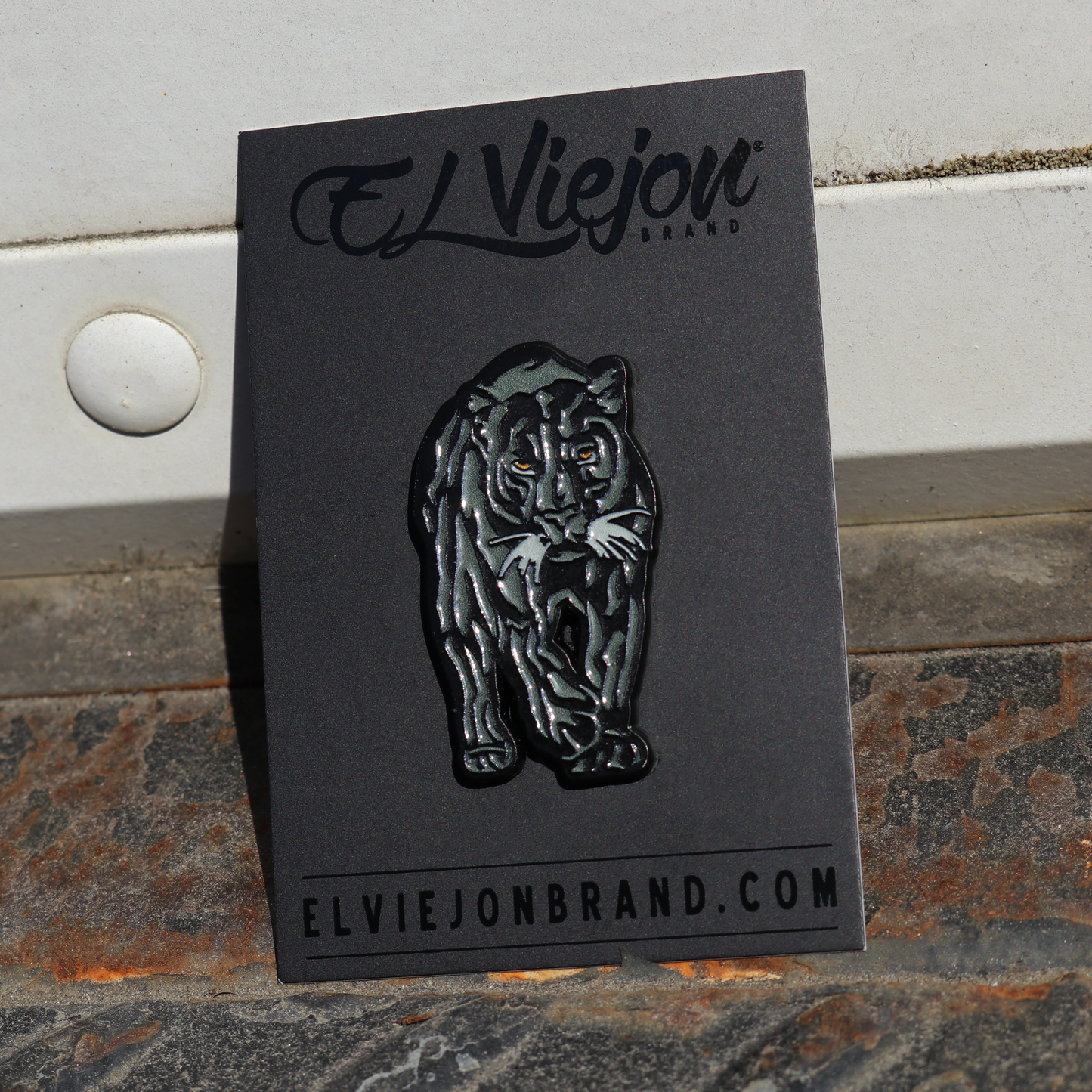 Black Pantera Negra enamel pin on a black card, featuring a walking panther with yellow eyes.