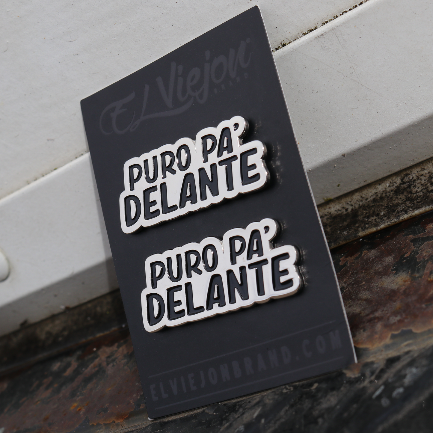 Two silver "Puro Pa' Delante" enamel pins on a black El Viejou Brand card.