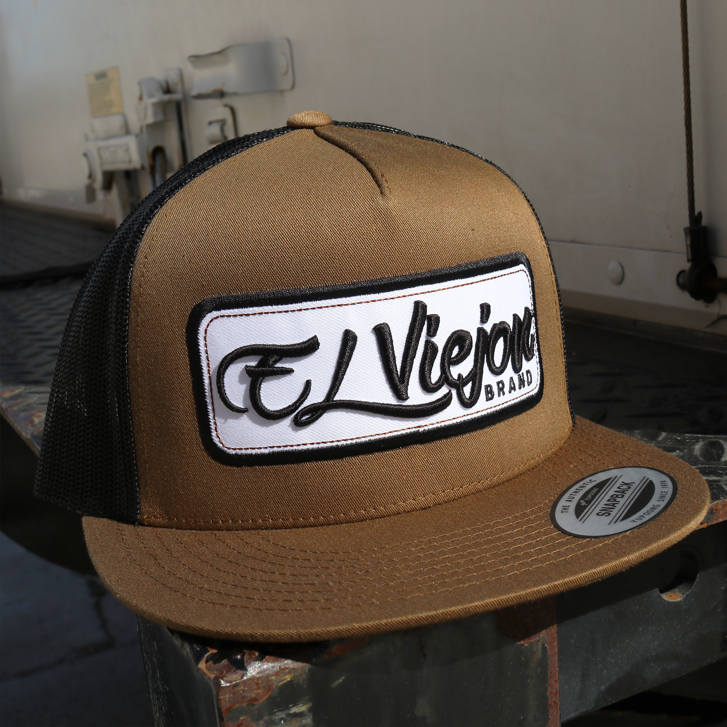 Coyote/black Yupoong Classic trucker hat with "El Viejon Brand" patch and flat visor.
