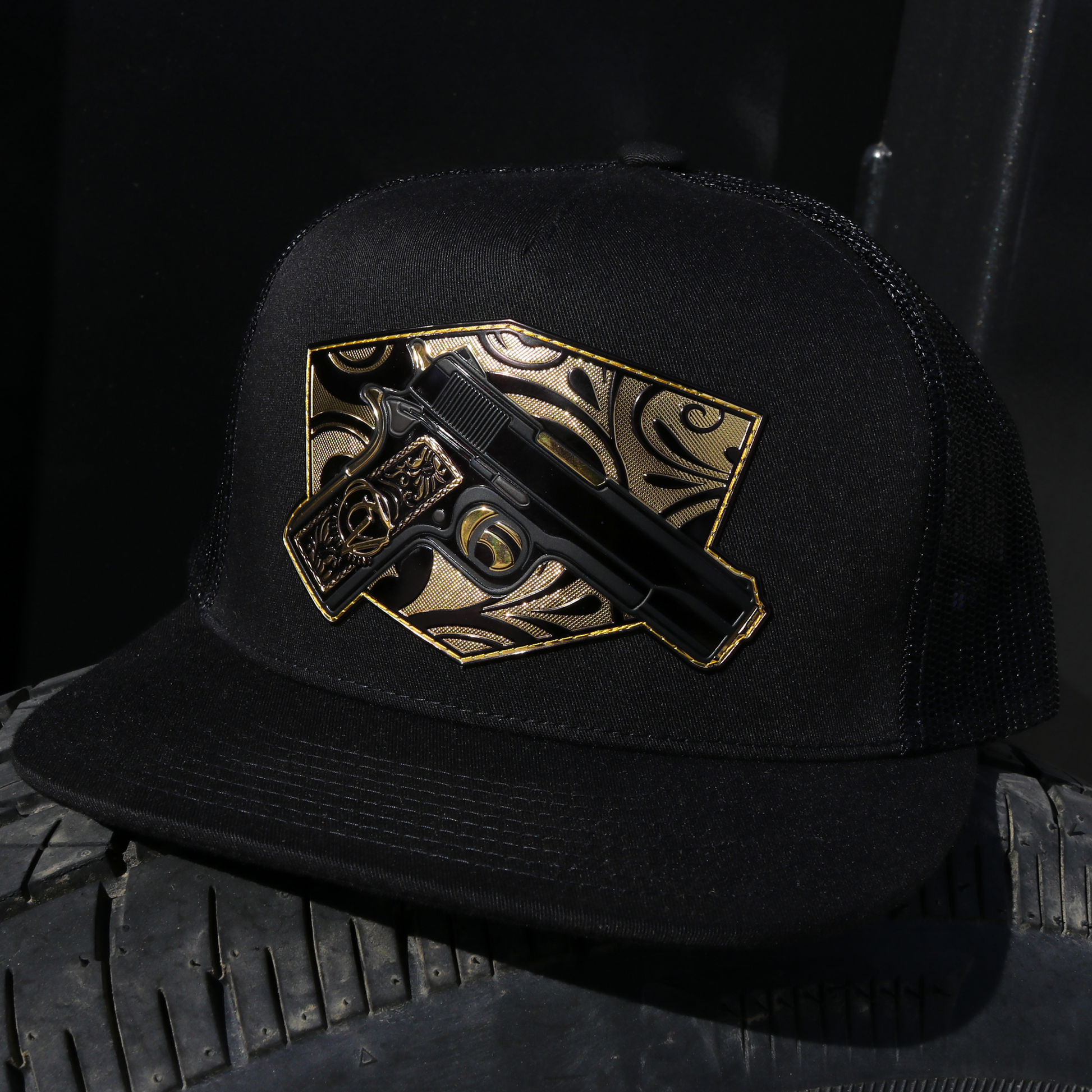 Cachas De Oro Black flat visor trucker hat with gold and black pistol emblem.