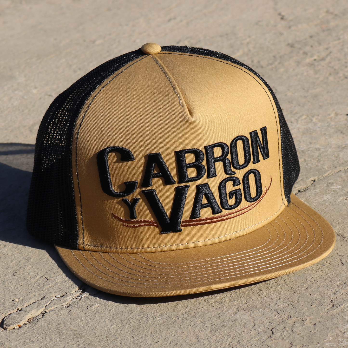 Cabron Y Vago mocha flat visor hat with black mesh back and embroidered logo.