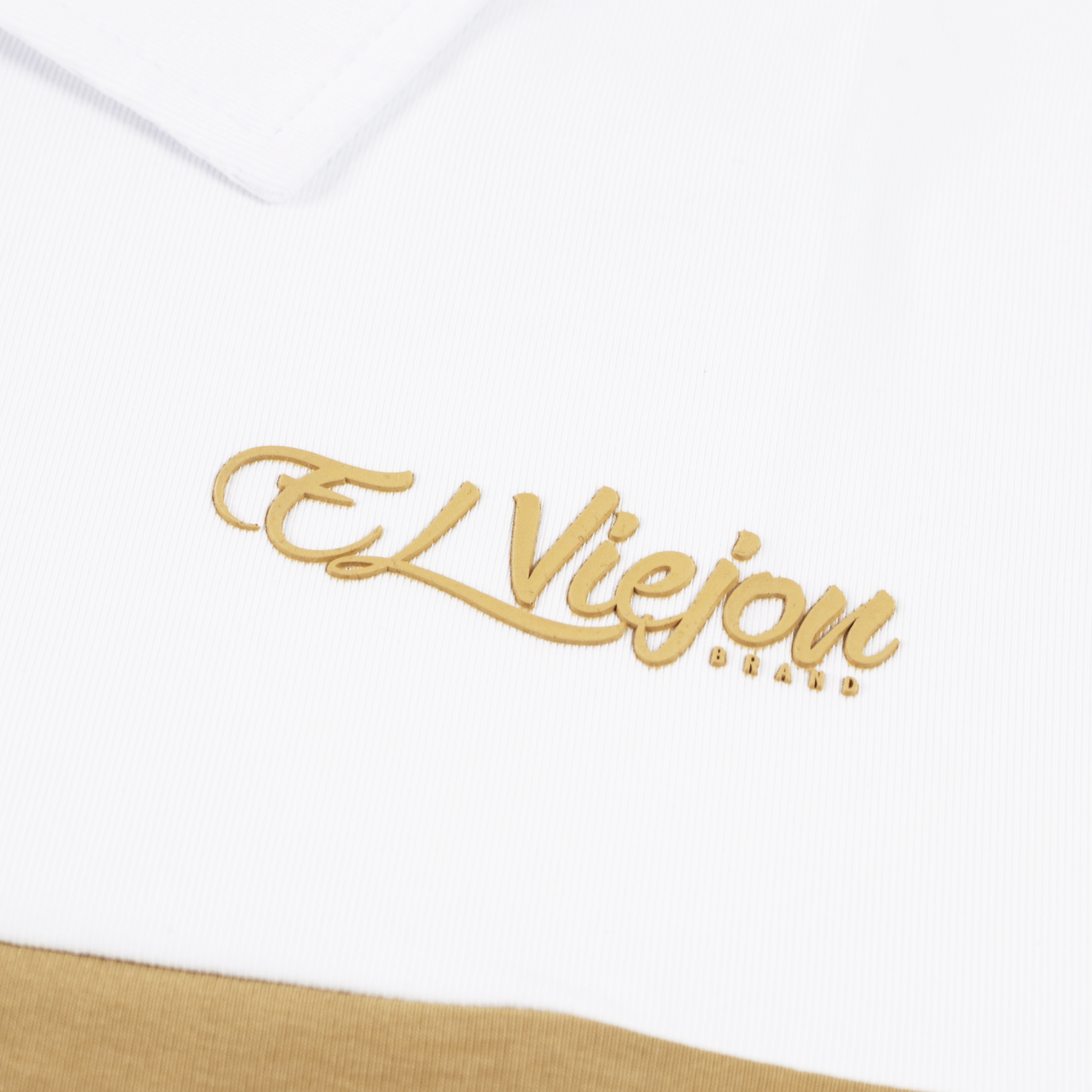 White and sand polo shirt with a gold 3D "El Viejon Brand" logo on the chest.