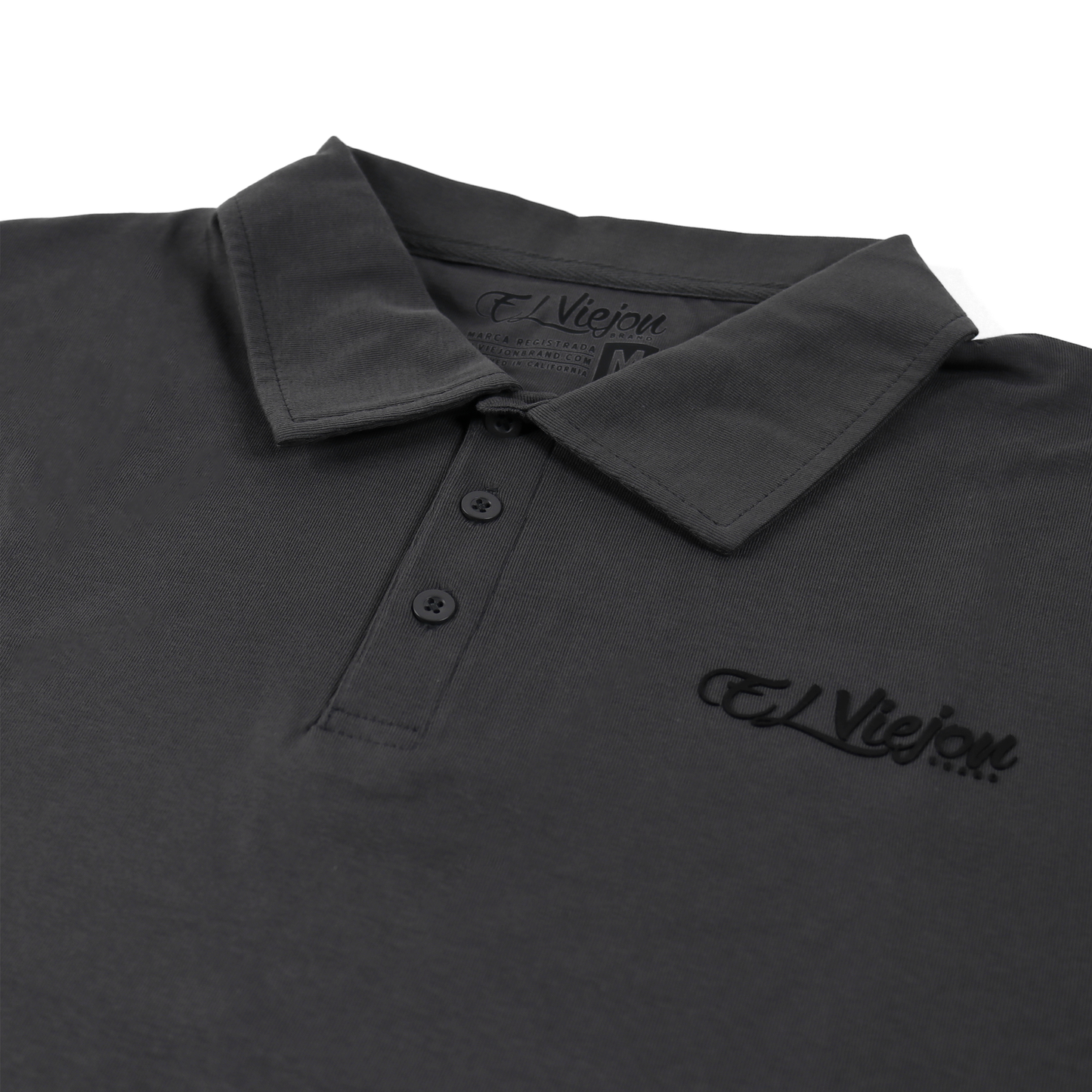 Charcoal polo shirt with 3-button placket and 3D vinyl "El Viejon Brand" logo.