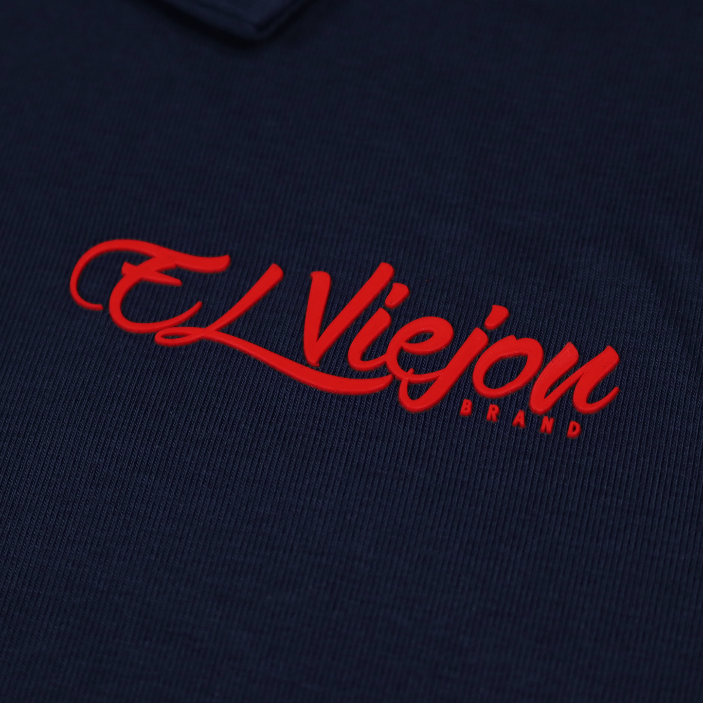 Navy blue polo shirt with a red 3D vinyl "El Viejon Brand" logo.