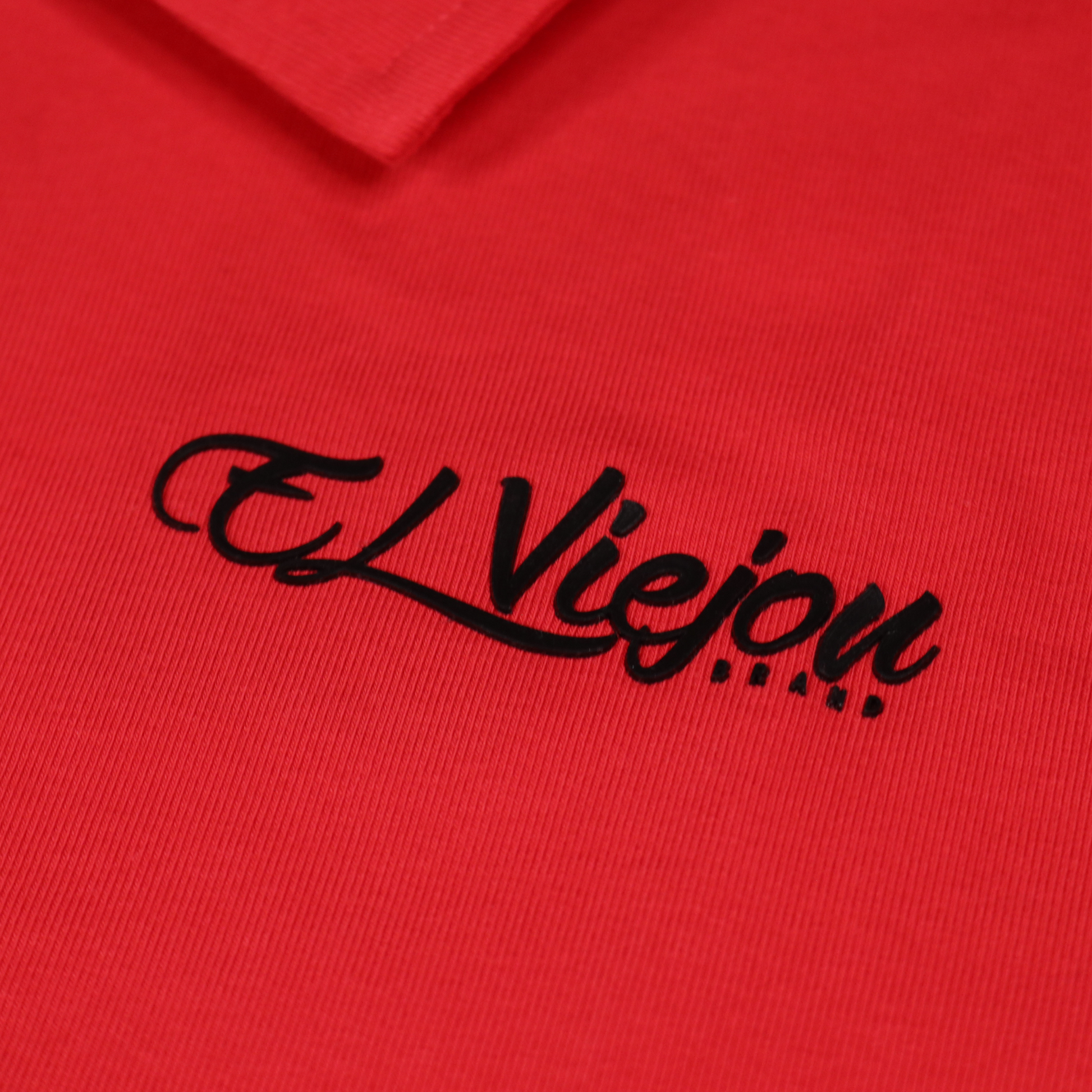 Red polo shirt with a black 3D vinyl "El Viejon Brand" logo and ribbed cotton-spandex fabric.