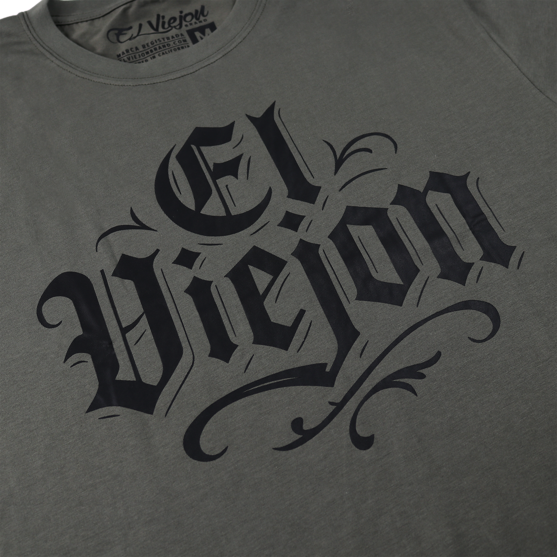 Charcoal gray 100% cotton "El Viejon" shirt with black gothic screen-printed text and neck label.