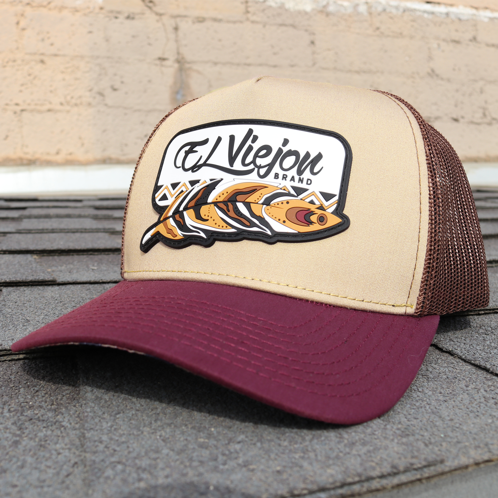 Nativo Plum/Khaki/Brown AVC hat with "El Viejon Brand" feather logo, pre-curved visor, and mesh back.