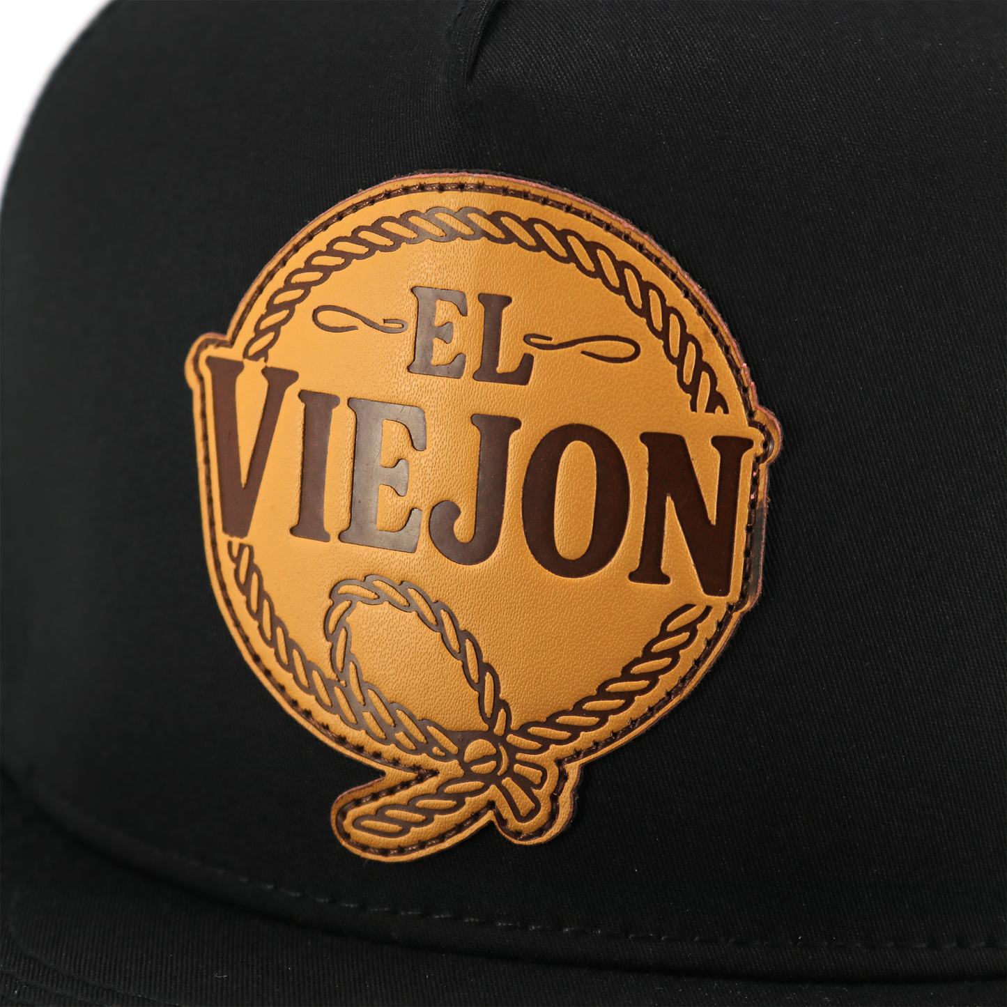 Black Rienda flat visor hat with a round brown leather patch featuring "EL VIEJON" and a rope design.