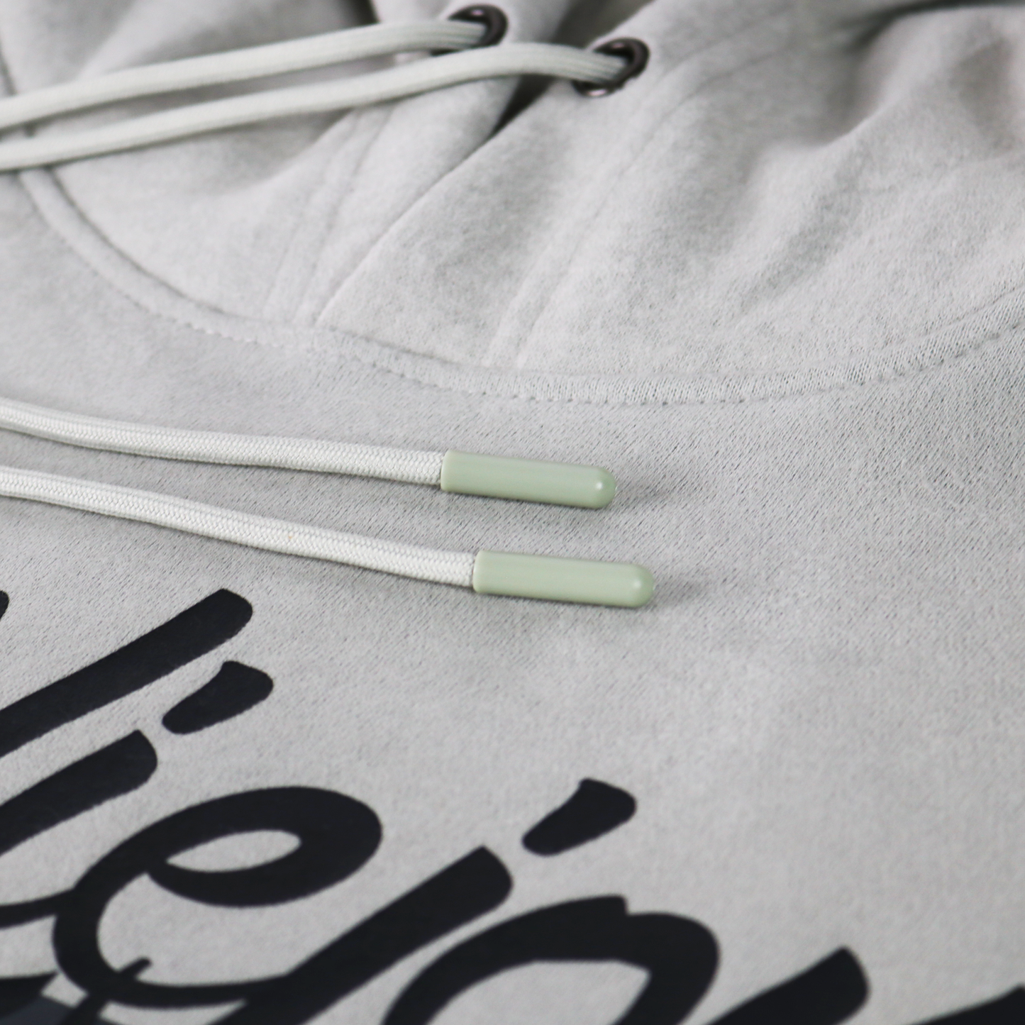 Light grey Alpha hoodie with white drawstrings, light green aglets, and a black screen-printed logo.