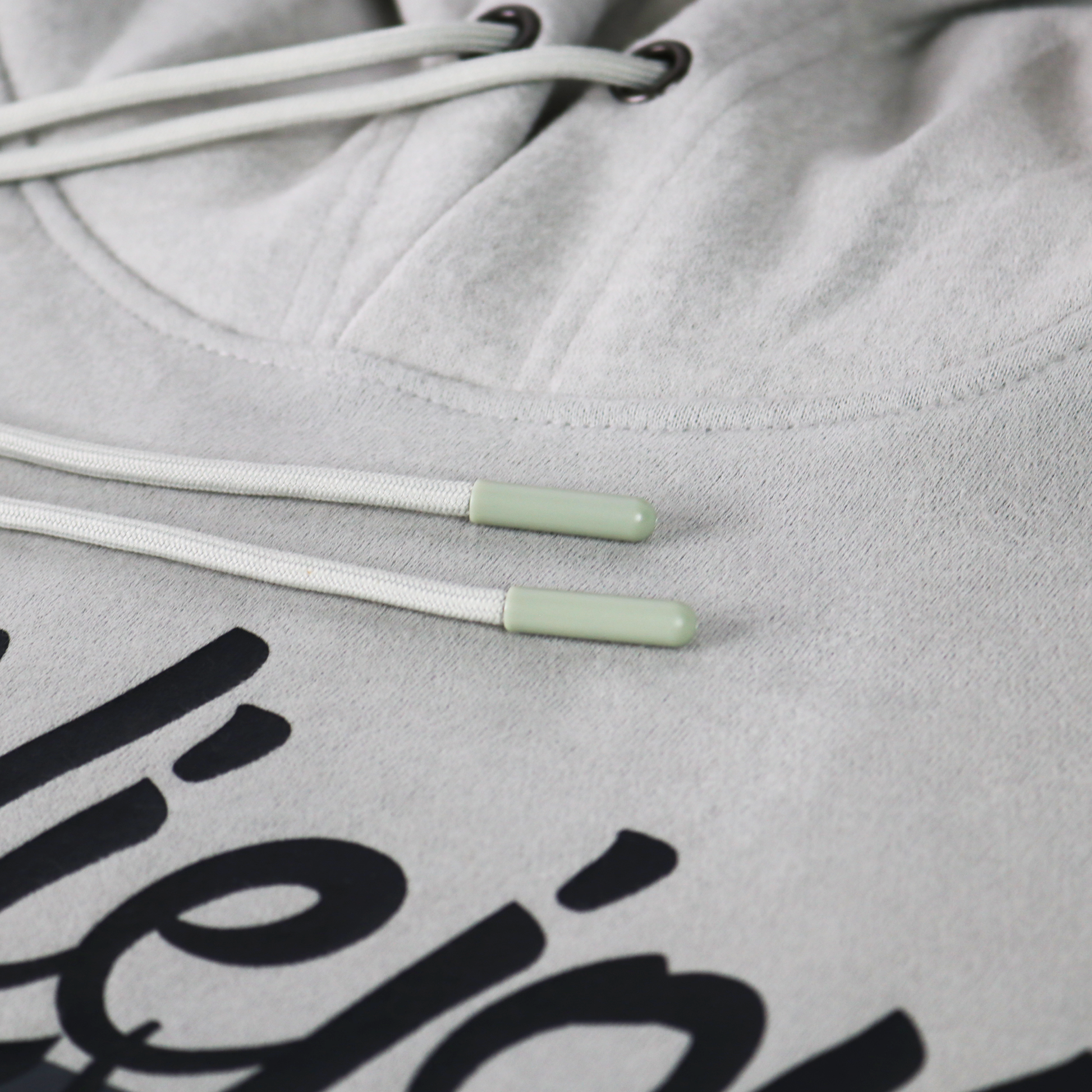 Light grey Alpha hoodie with white drawstrings, light green aglets, and a black screen-printed logo.