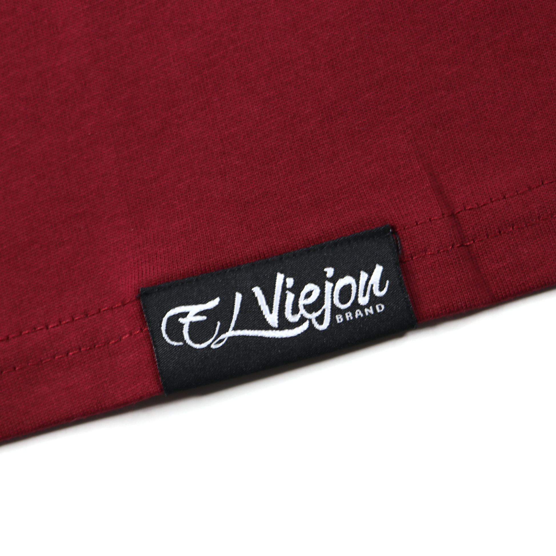 Close-up of a maroon 100% cotton Alpha shirt with a black "El Viejou Brand" tag.