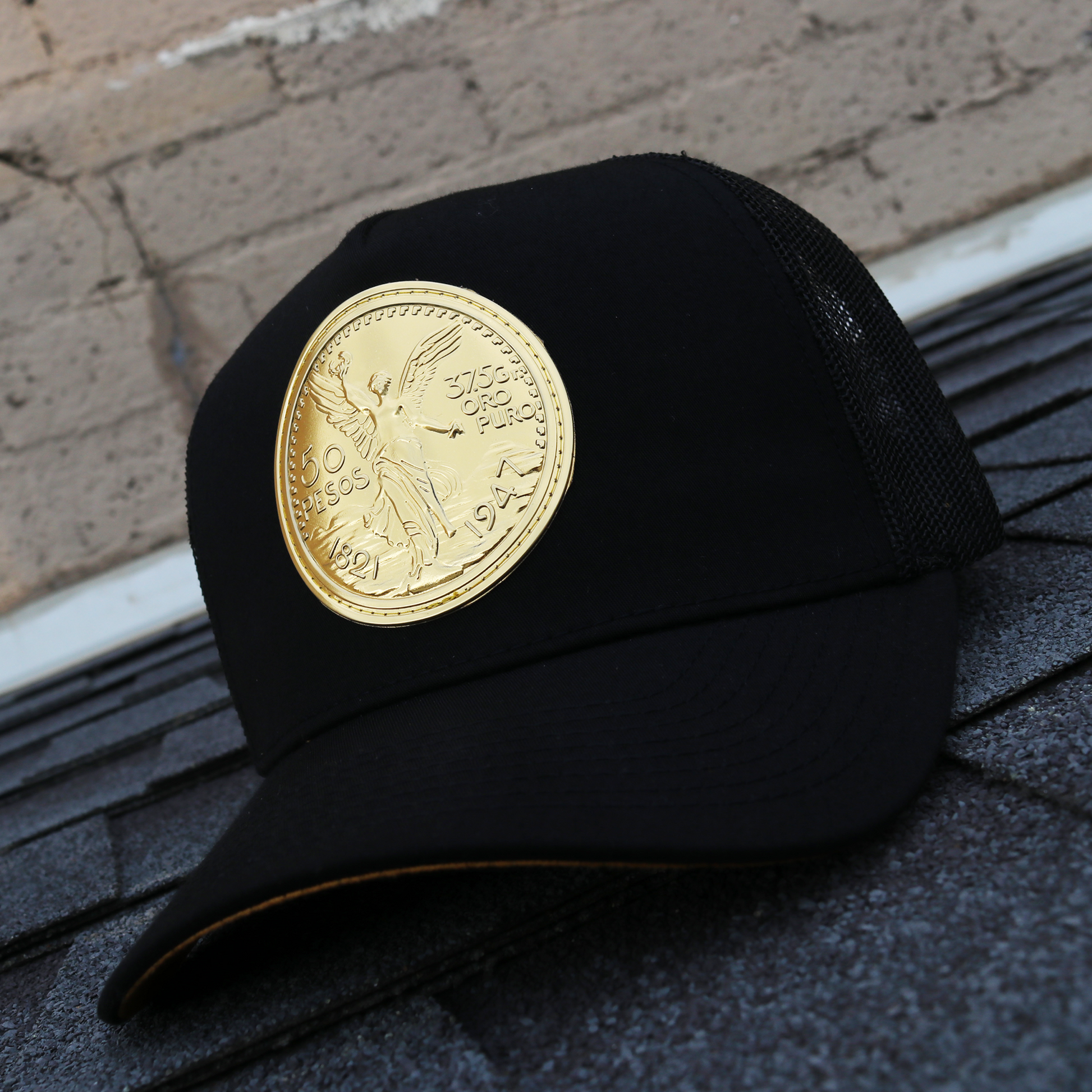 Black AVC hat with black mesh, pre-curved visor, and a prominent gold coin design.