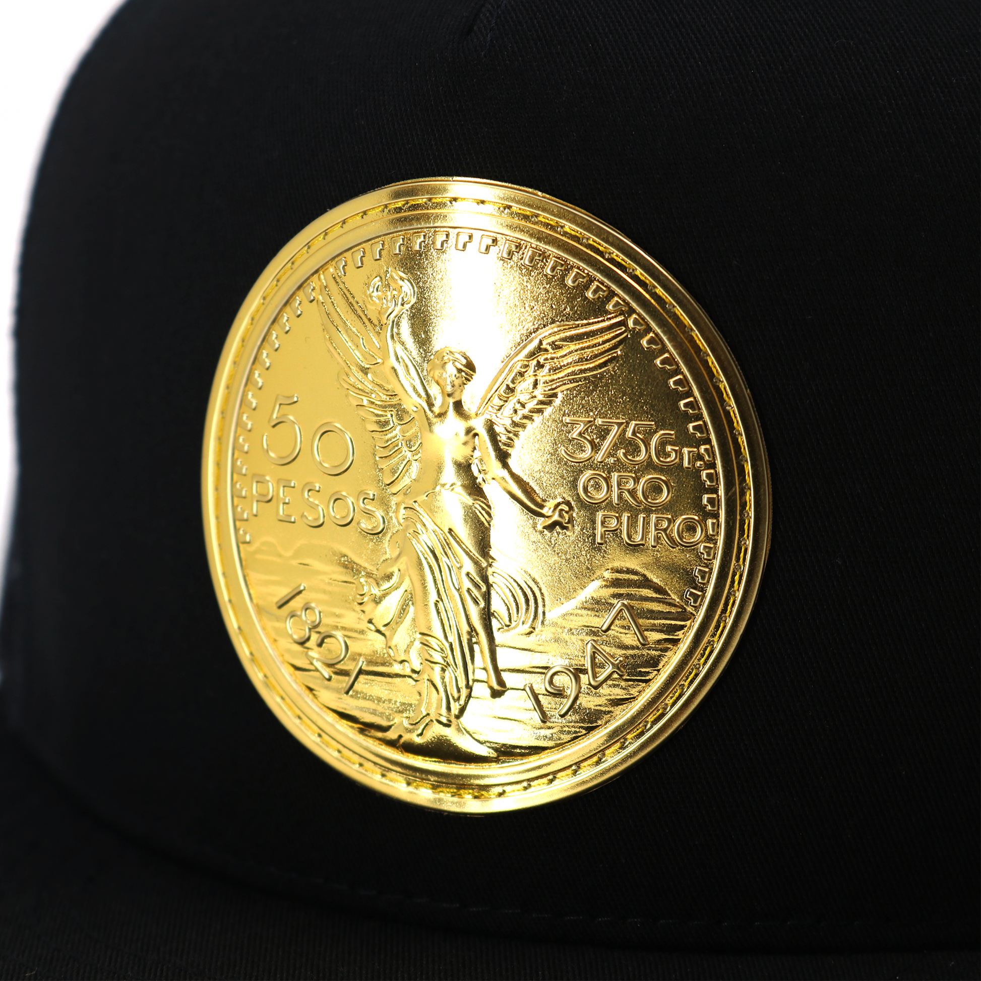 El Cente Black flat visor hat with a large, shiny gold coin emblem featuring an angel.