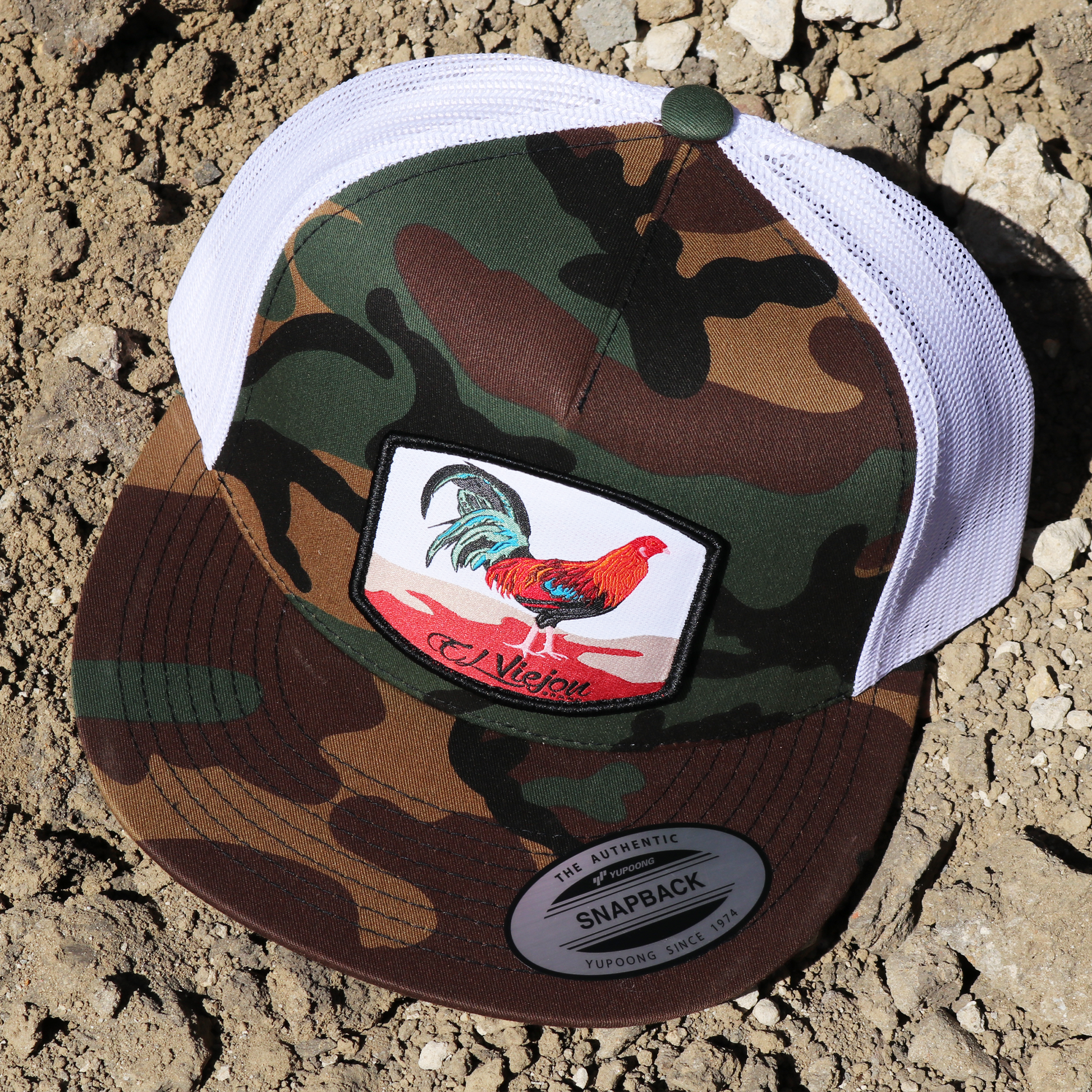 Gallo Camo/White Yupoong trucker hat with flat visor and rooster patch.