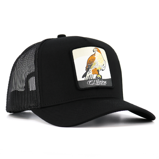 Halcon Black AVC hat: high profile, 5-panel trucker cap with black mesh and a hawk patch.