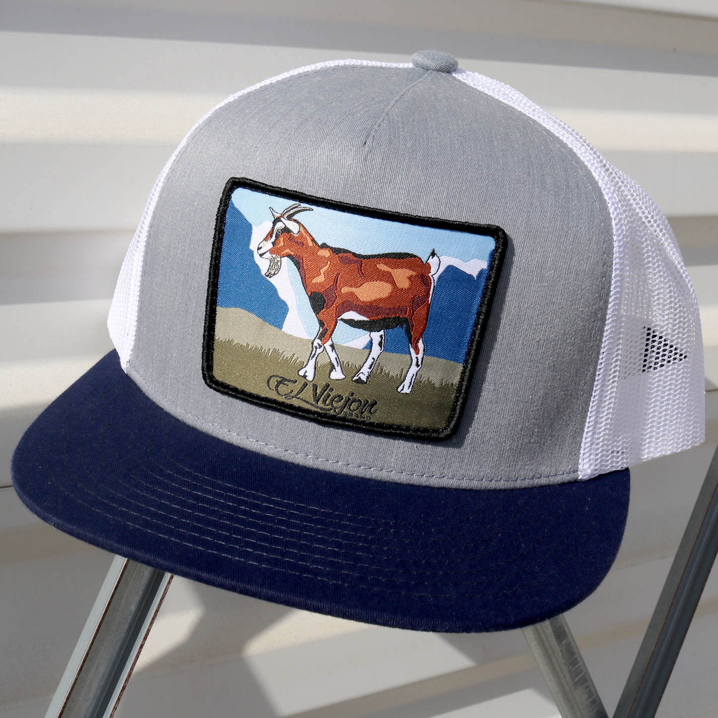 Chivo Navy/Heather/White flat visor trucker hat with embroidered goat patch.