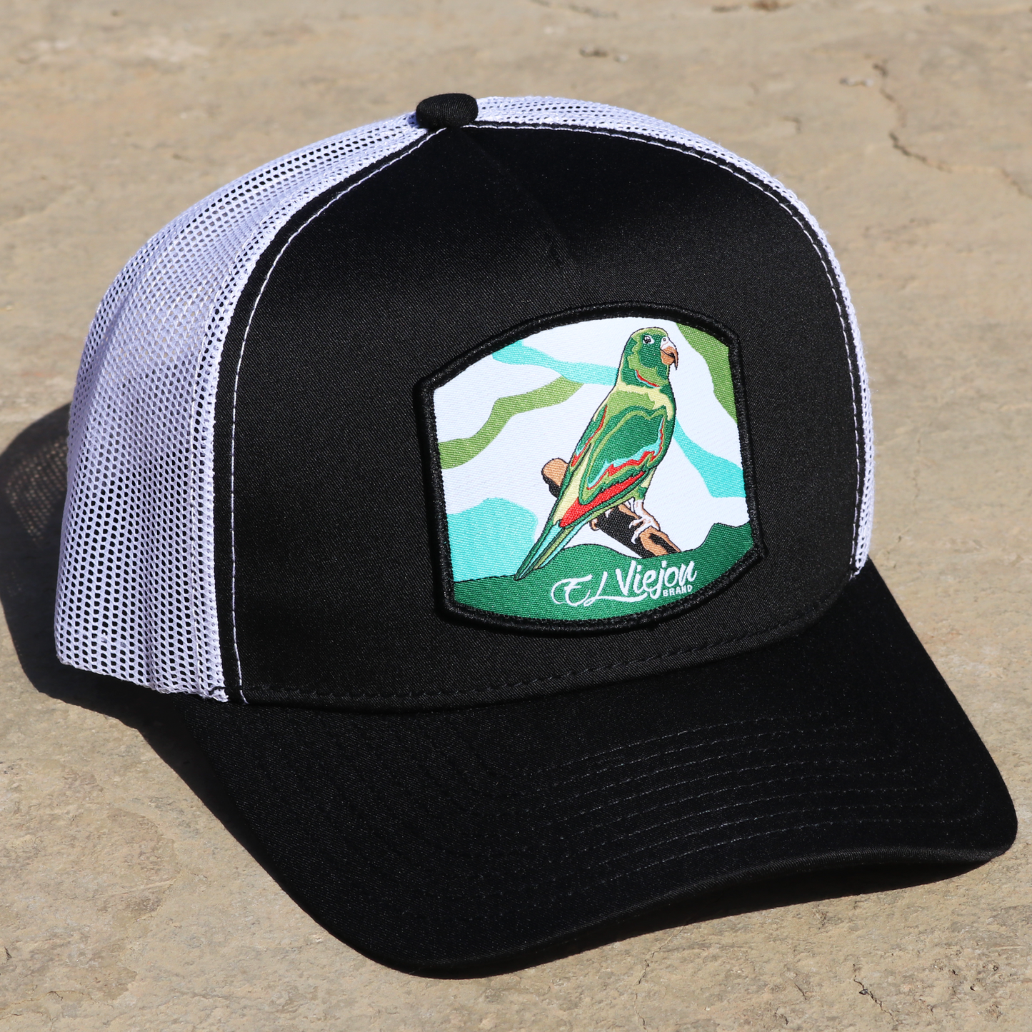 Perico Black/White AVC hat with green parrot patch, high profile, pre-curved visor, and adjustable snapback.