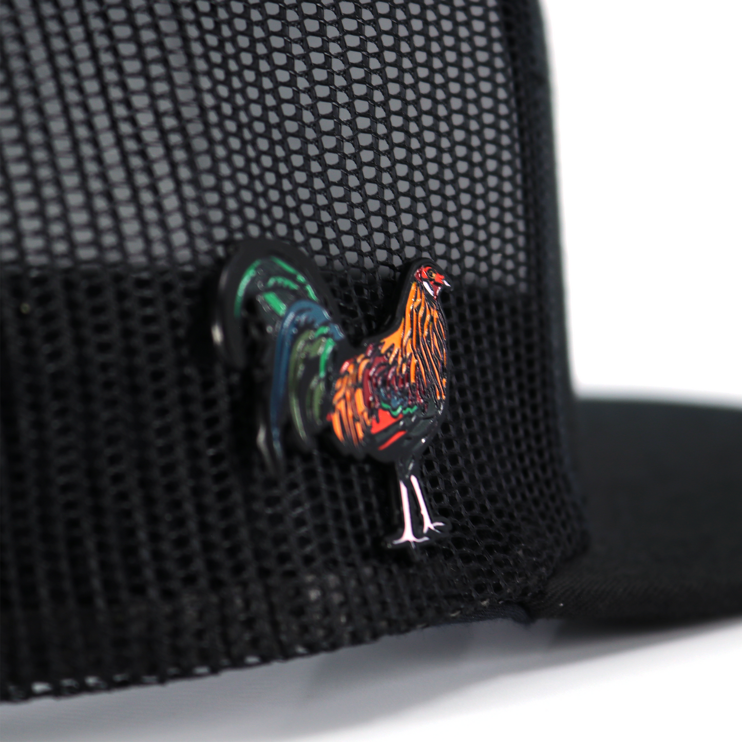 Gallo Colorado enamel pin with vibrant red, orange, green, and blue details, attached to a black mesh hat.
