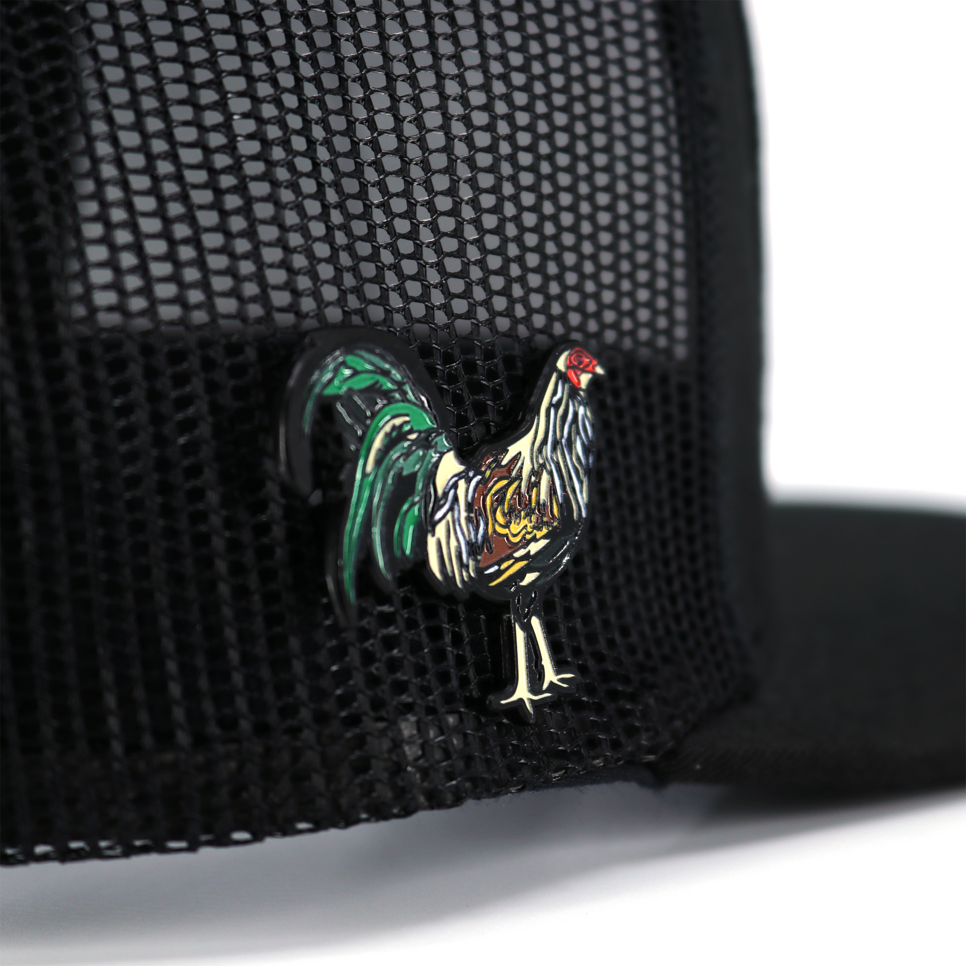Gallo Giro enamel pin with colorful rooster design, attached to a black mesh hat.