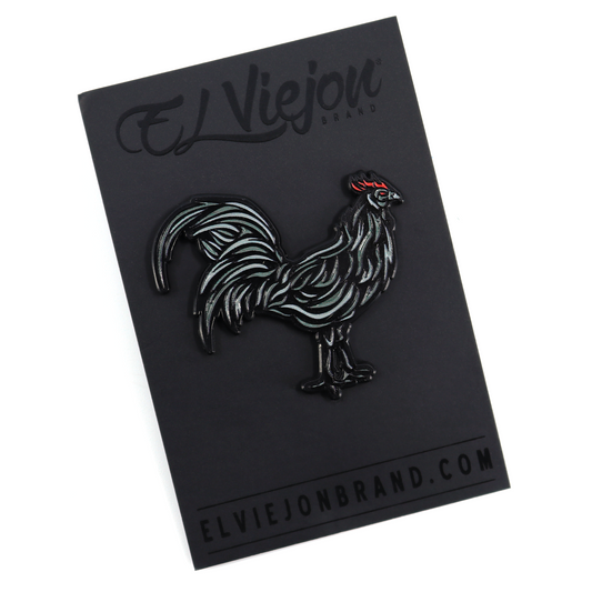 Black enamel Gallo Negro pin with red comb on a black backing card.