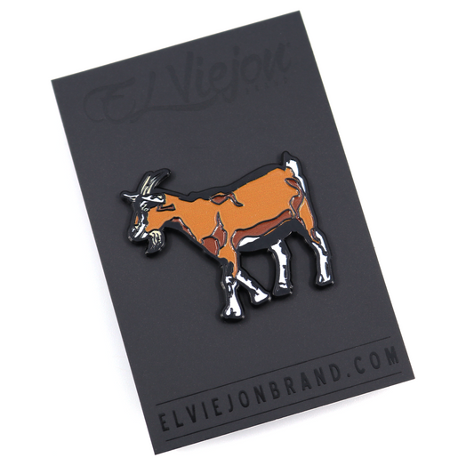 Chivo Pin: brown and white goat enamel pin on a black backing card.