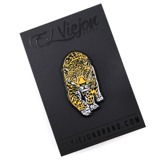 Jaguar enamel pin with yellow, black, and white spots on a black backing card.