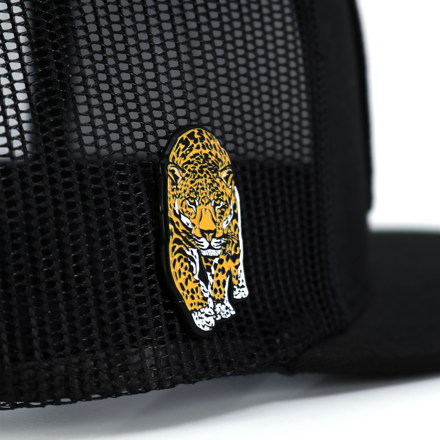 Black and yellow jaguar enamel pin with rubber clutch, attached to a black mesh hat.