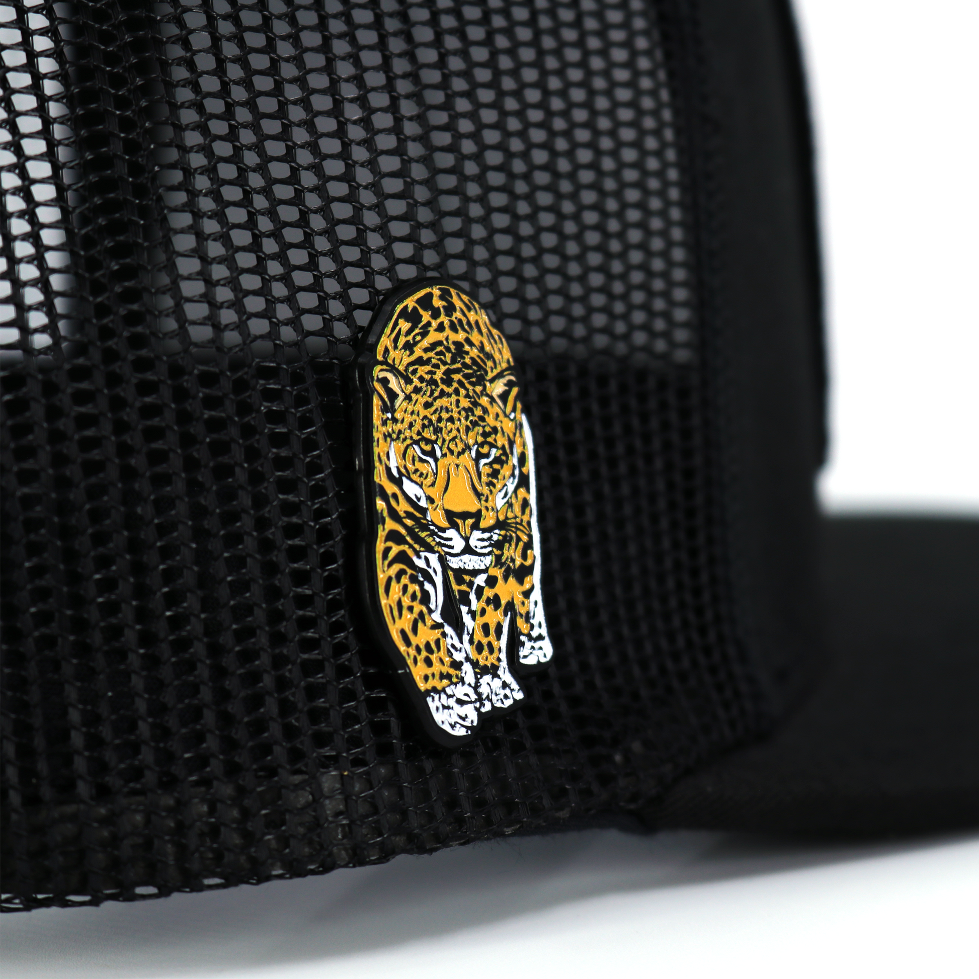 Black and yellow jaguar enamel pin with rubber clutch, attached to a black mesh hat.