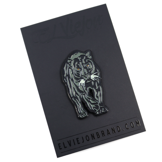 Black Pantera Negra enamel pin with green highlights and orange eyes, on a black card.