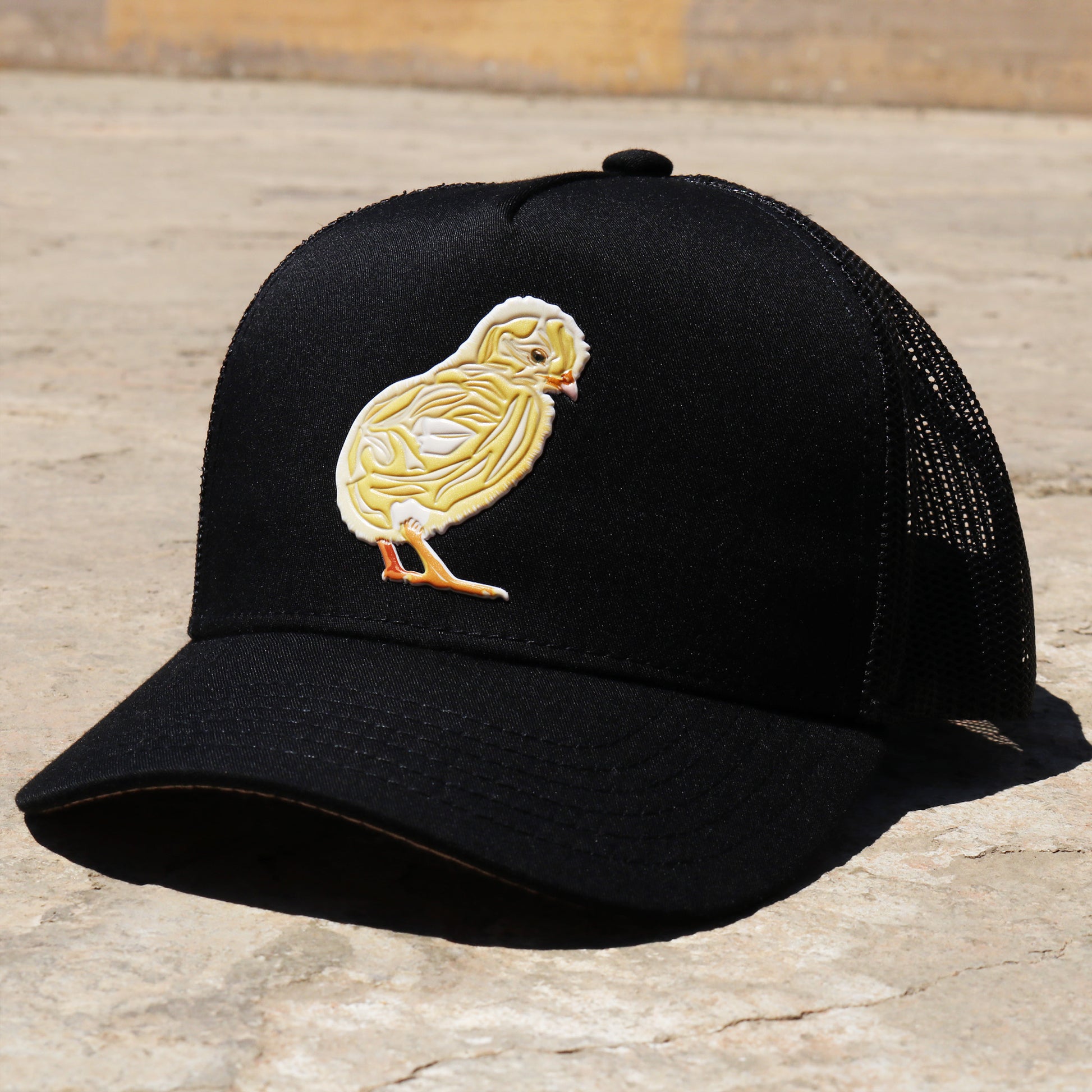 Pollito Black kids trucker hat with a yellow chick design, curved visor, and mesh back.