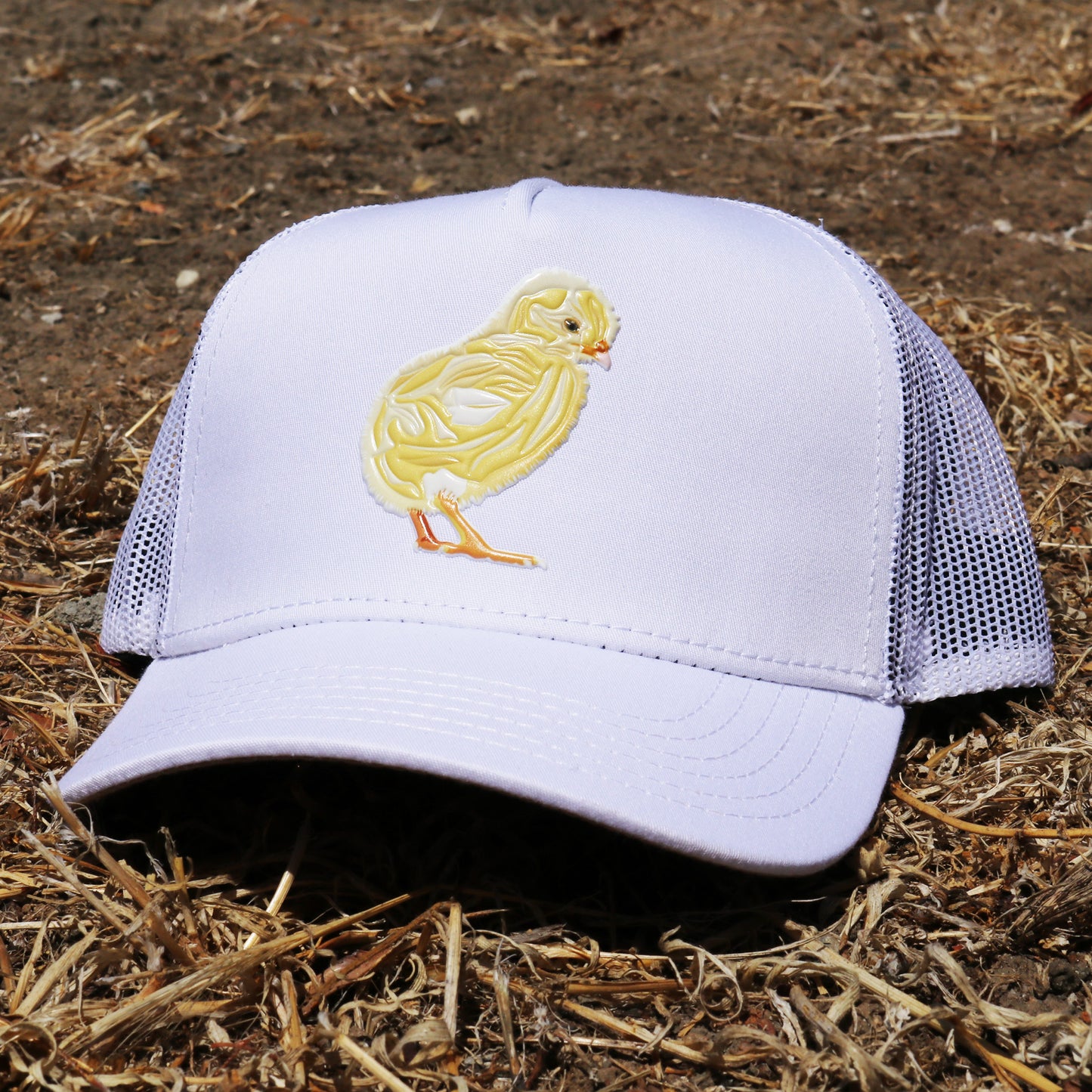 White kids trucker hat with a yellow chick design, curved visor, and mesh back.