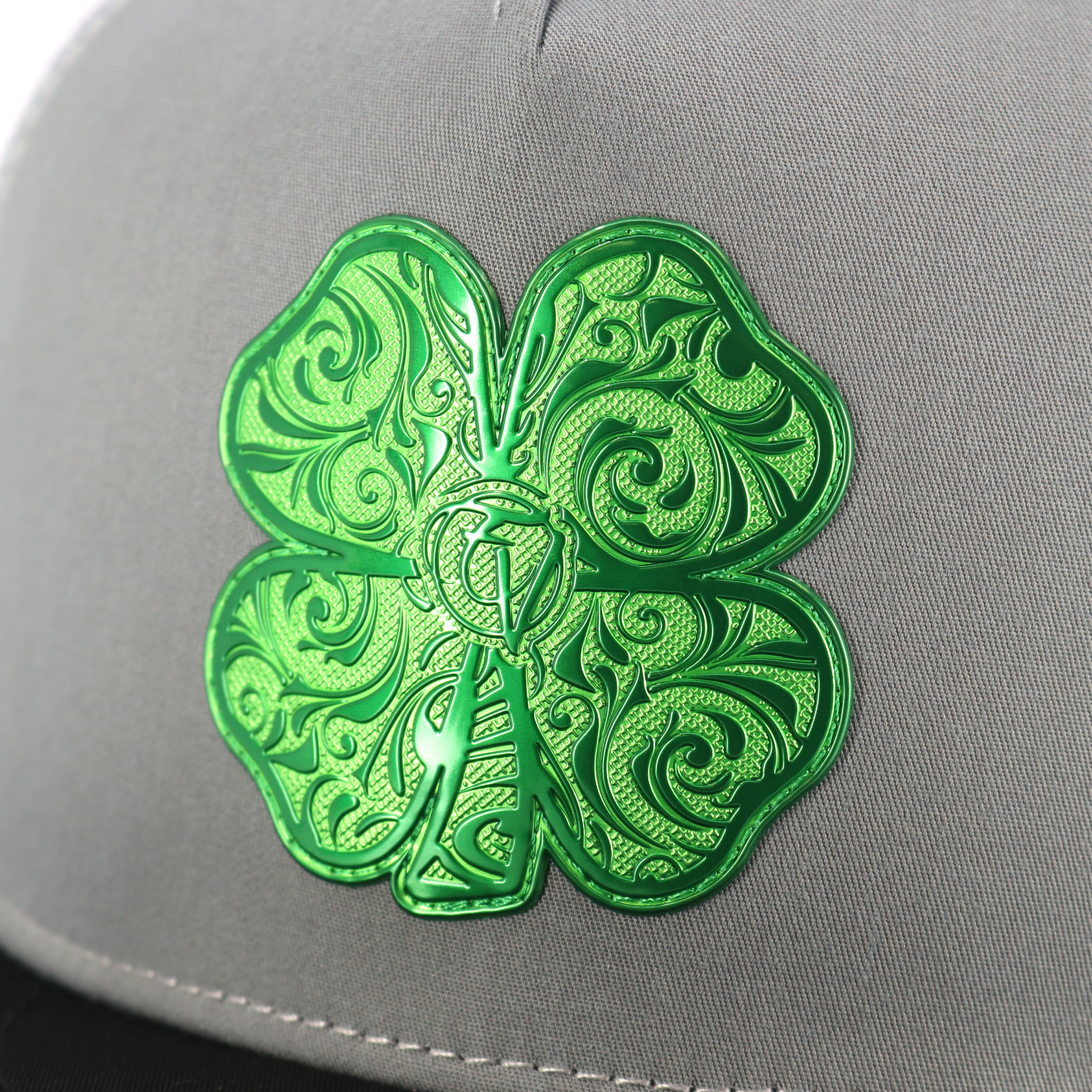 Trebol Black/Grey/White flat visor hat with a vibrant green ornate four-leaf clover emblem.