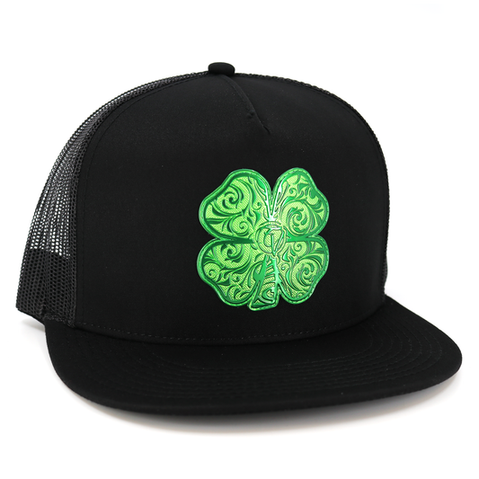 Trebol Black flat visor hat with green embroidered four-leaf clover, black mesh back, and snapback closure.