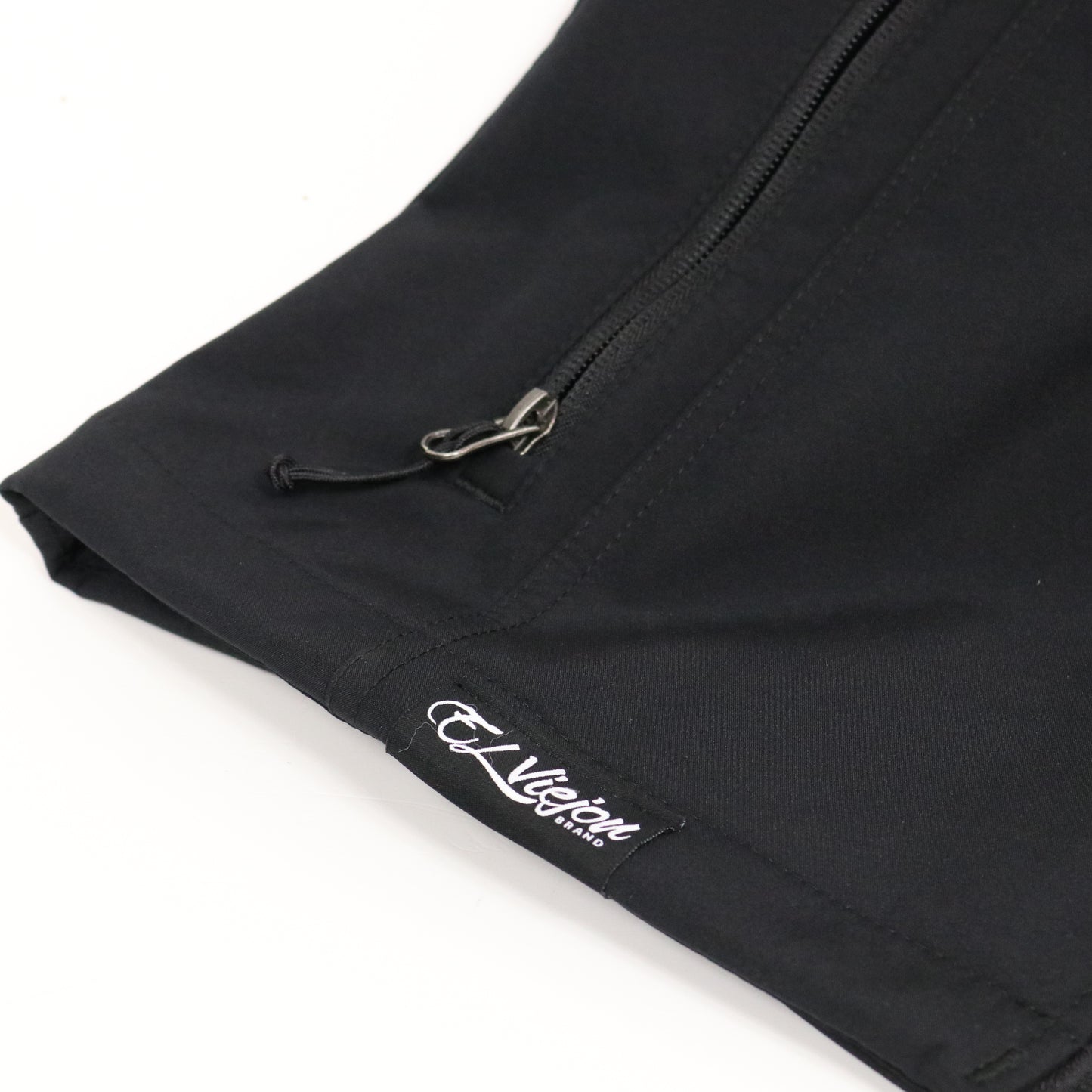 Black El Viejon Brand Vest, close-up of the lower left front with white logo and zippered pocket.