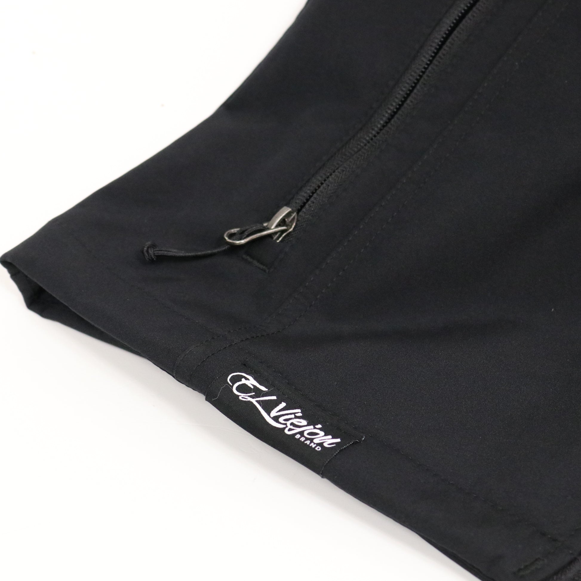 Black El Viejon Brand Vest, close-up of the lower left front with white logo and zippered pocket.