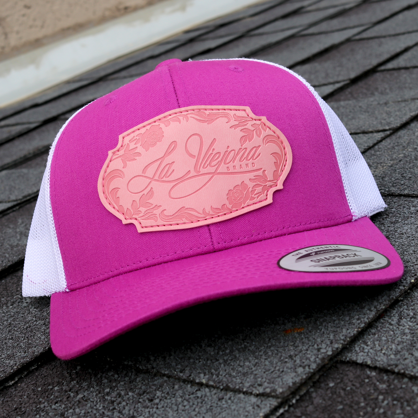 La Viejona Floral Magenta/White Yupoong Classic trucker hat with pink embossed logo.
