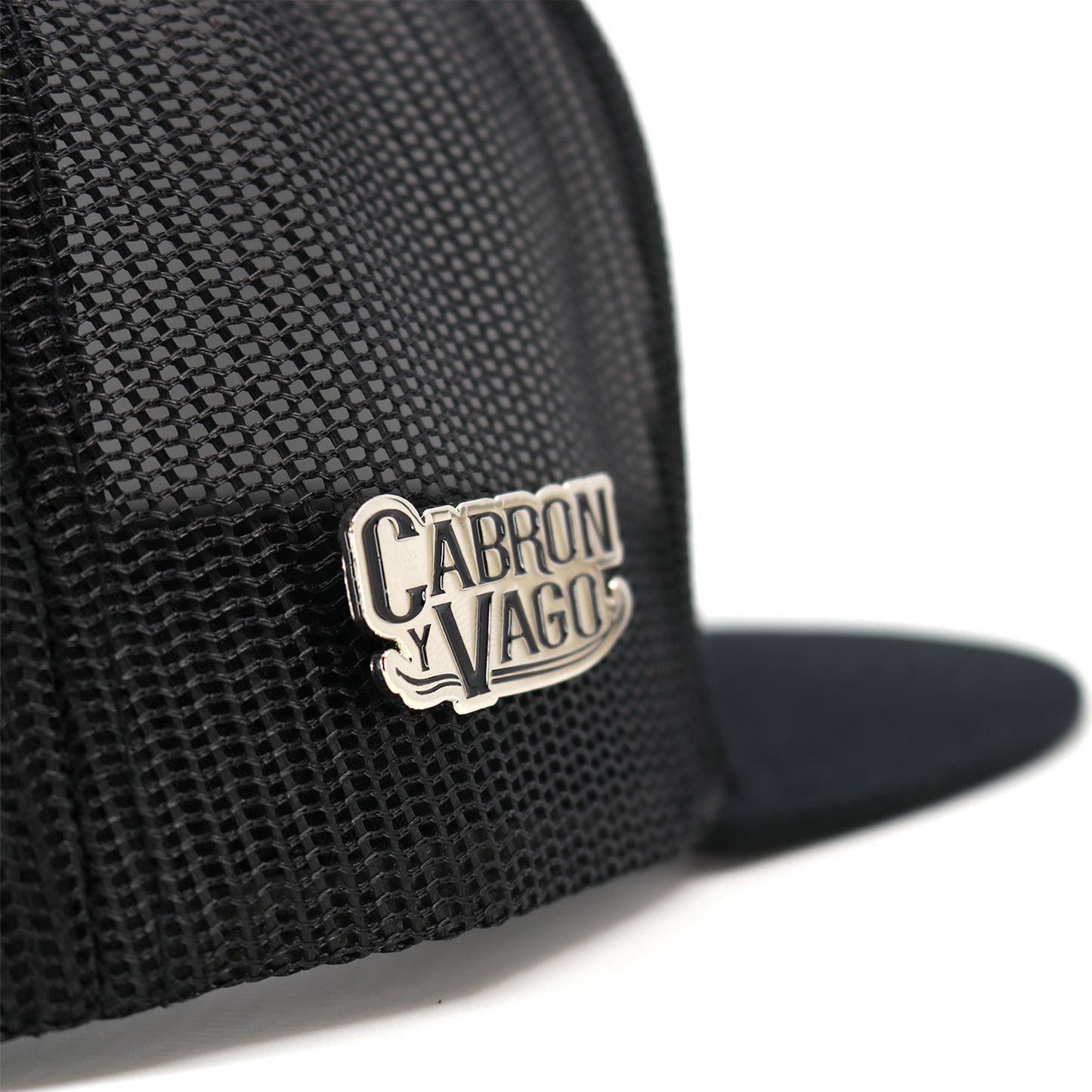 Silver Cabron y Vago pin attached to a black mesh hat, showcasing its metallic finish and detailed lettering.