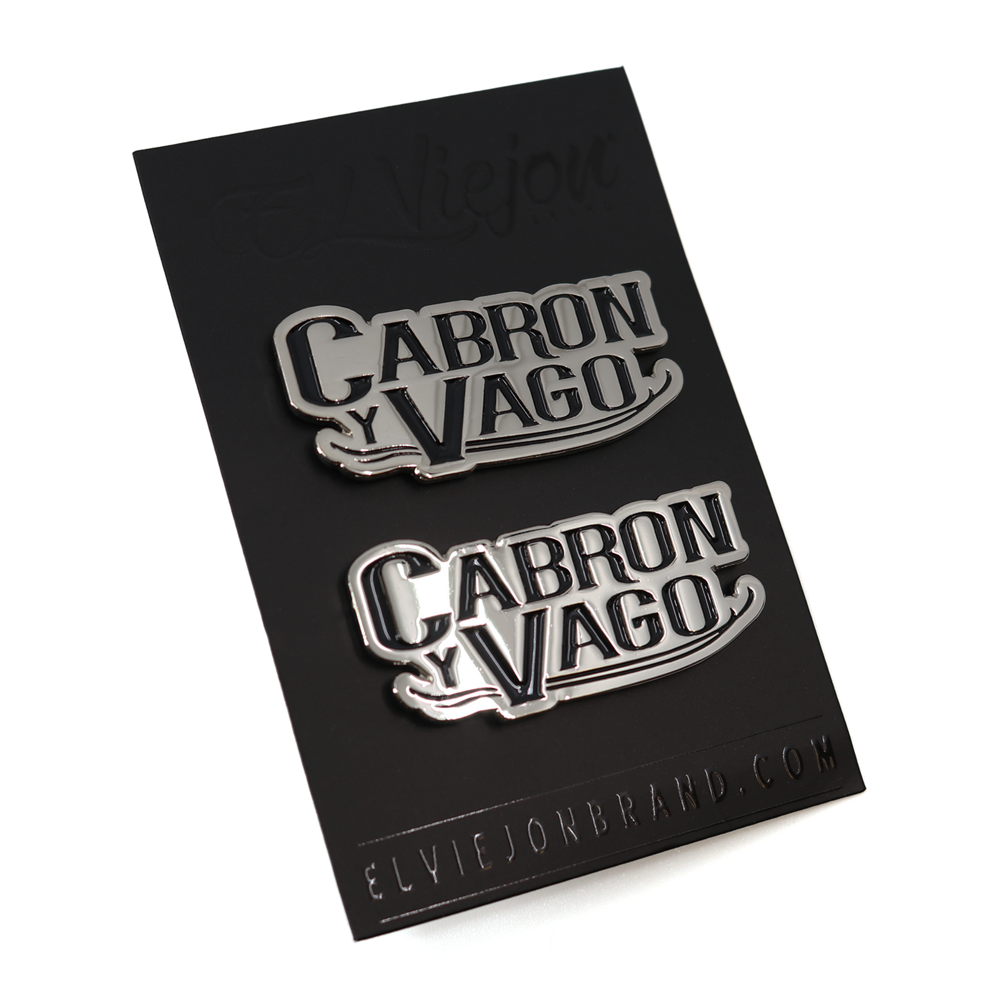 Two silver "Cabron y Vago" pins on a black card, featuring a bold, stylized font.