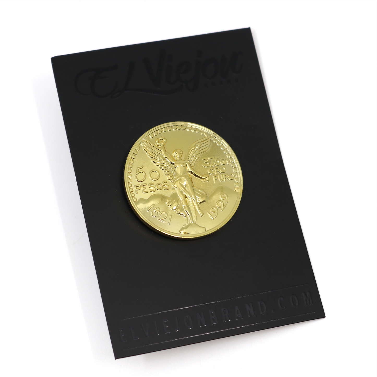 El Cente gold-colored metal pin, shaped like a 50 Pesos coin with an angel design, on a black card.