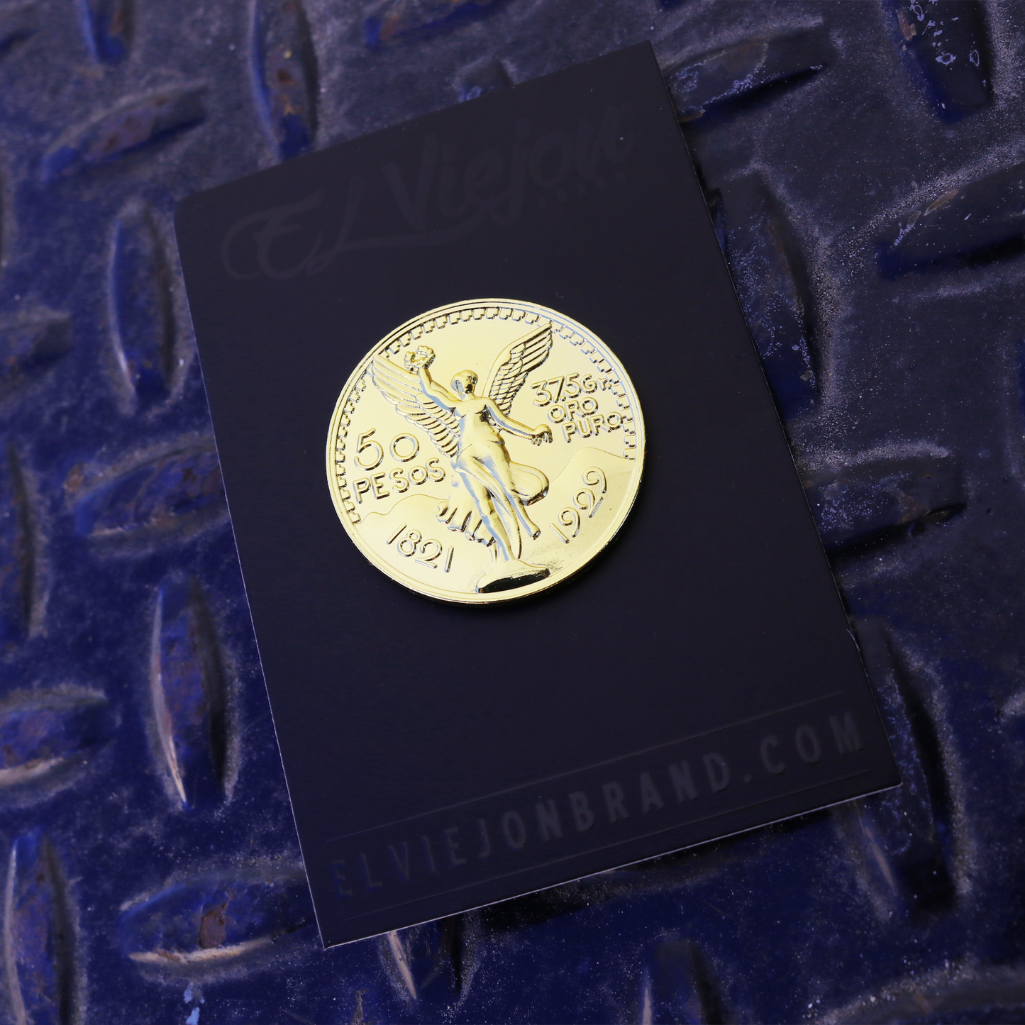 Shiny gold El Cente pin with winged Victoria design on black card, rubber clutch.