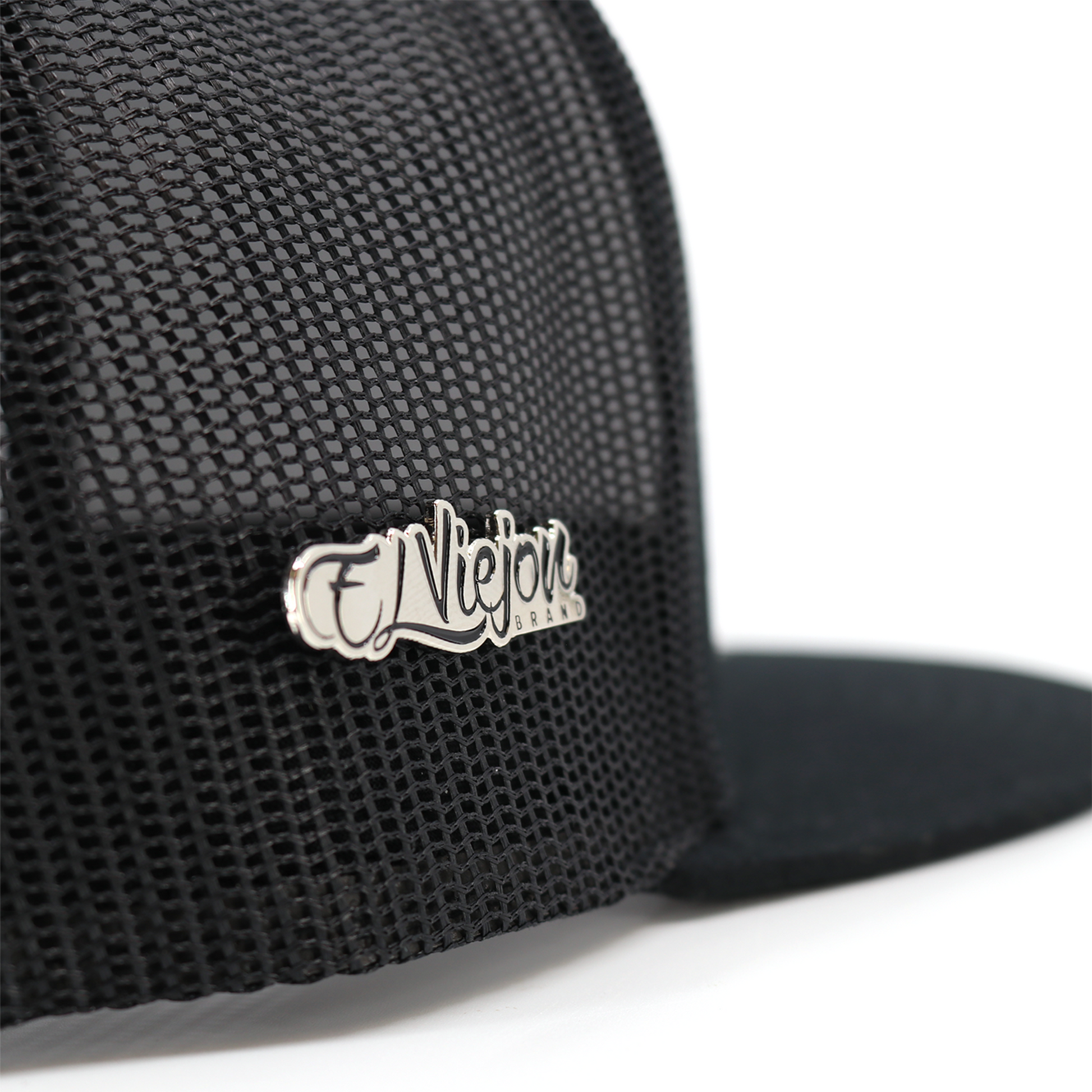 Silver El Viejon Brand pin attached to a black mesh trucker hat.