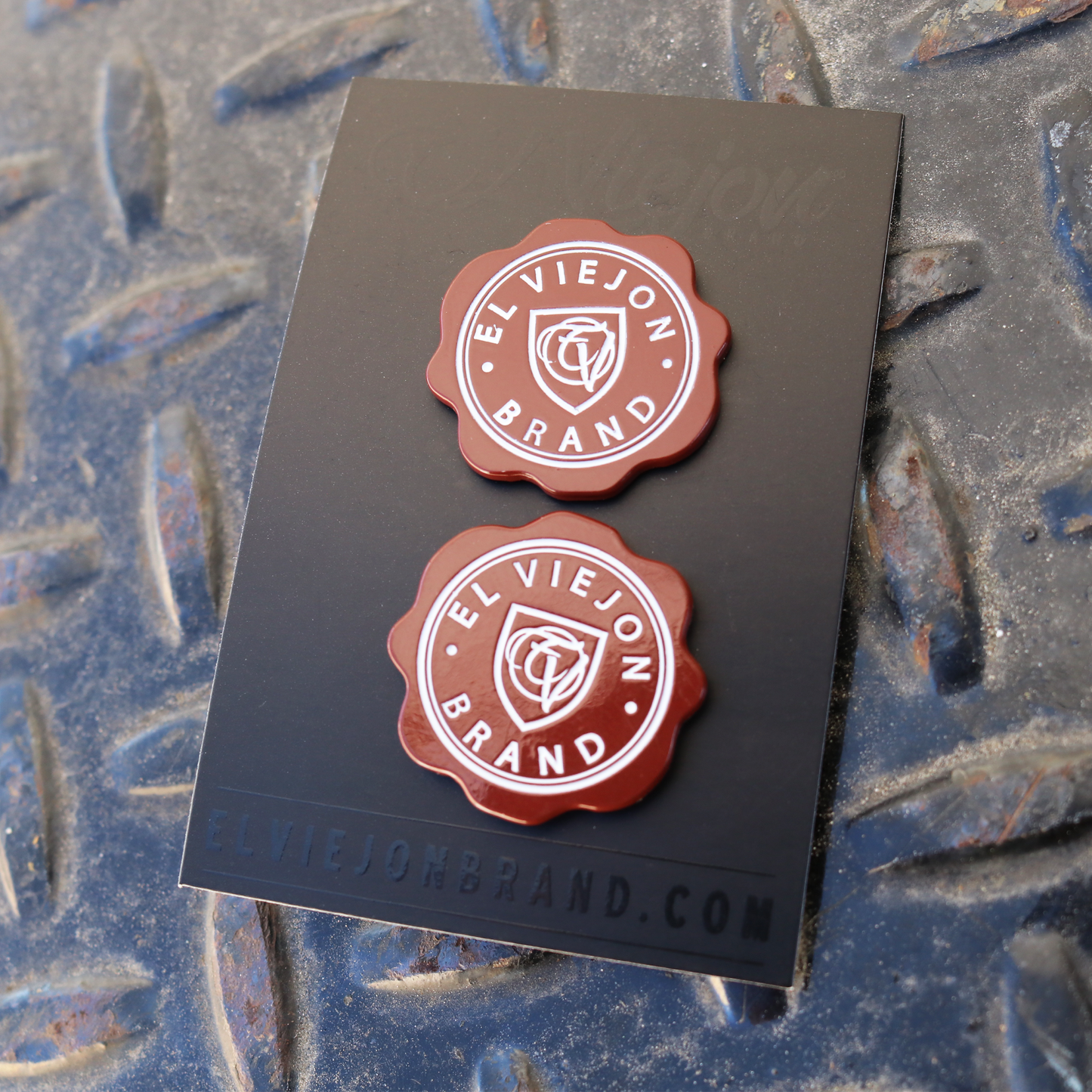 Two glossy red El Viejon Brand enamel pins on a black card, with a rubber clutch.